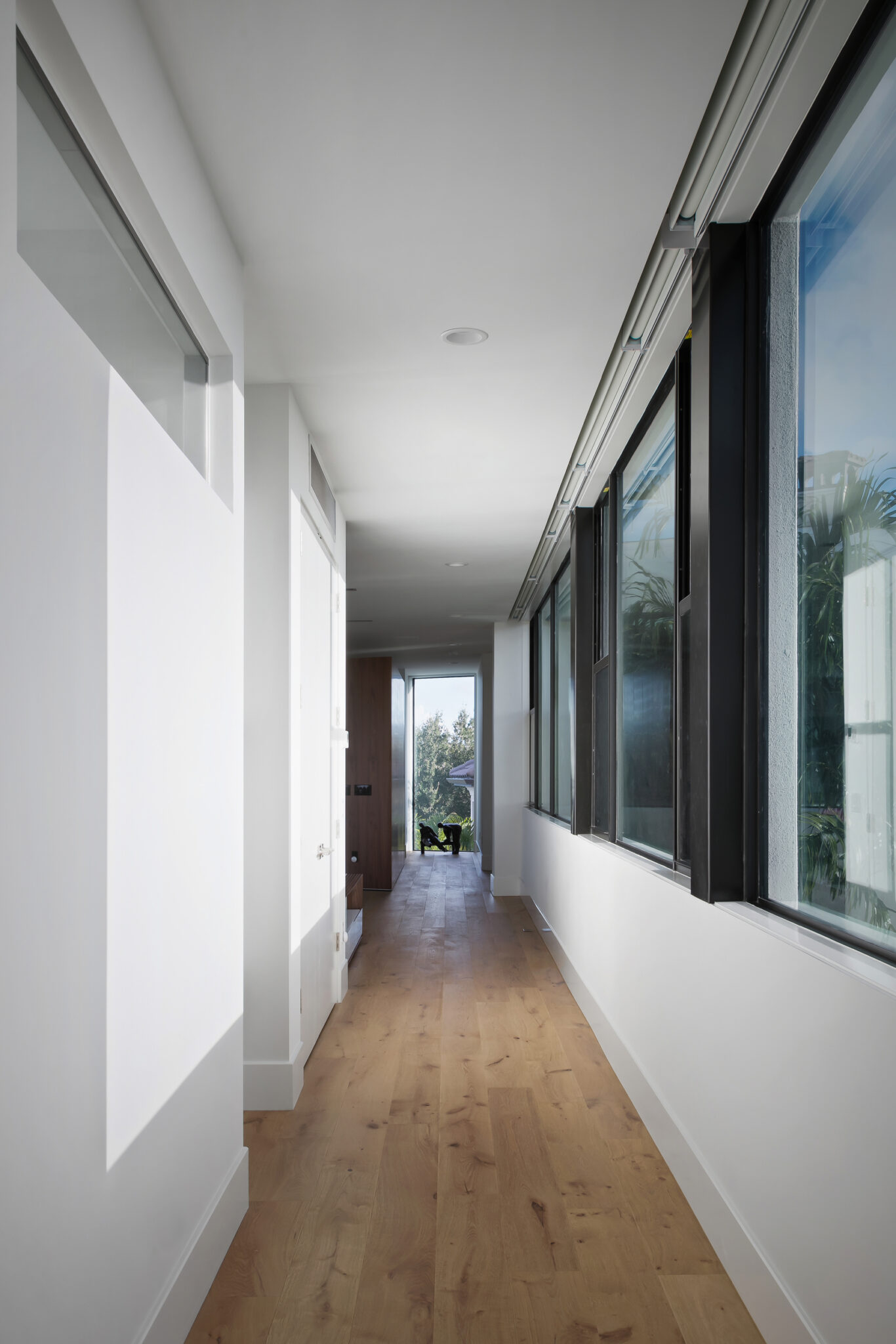 Gallery hallway lined with tall windows and oak floors