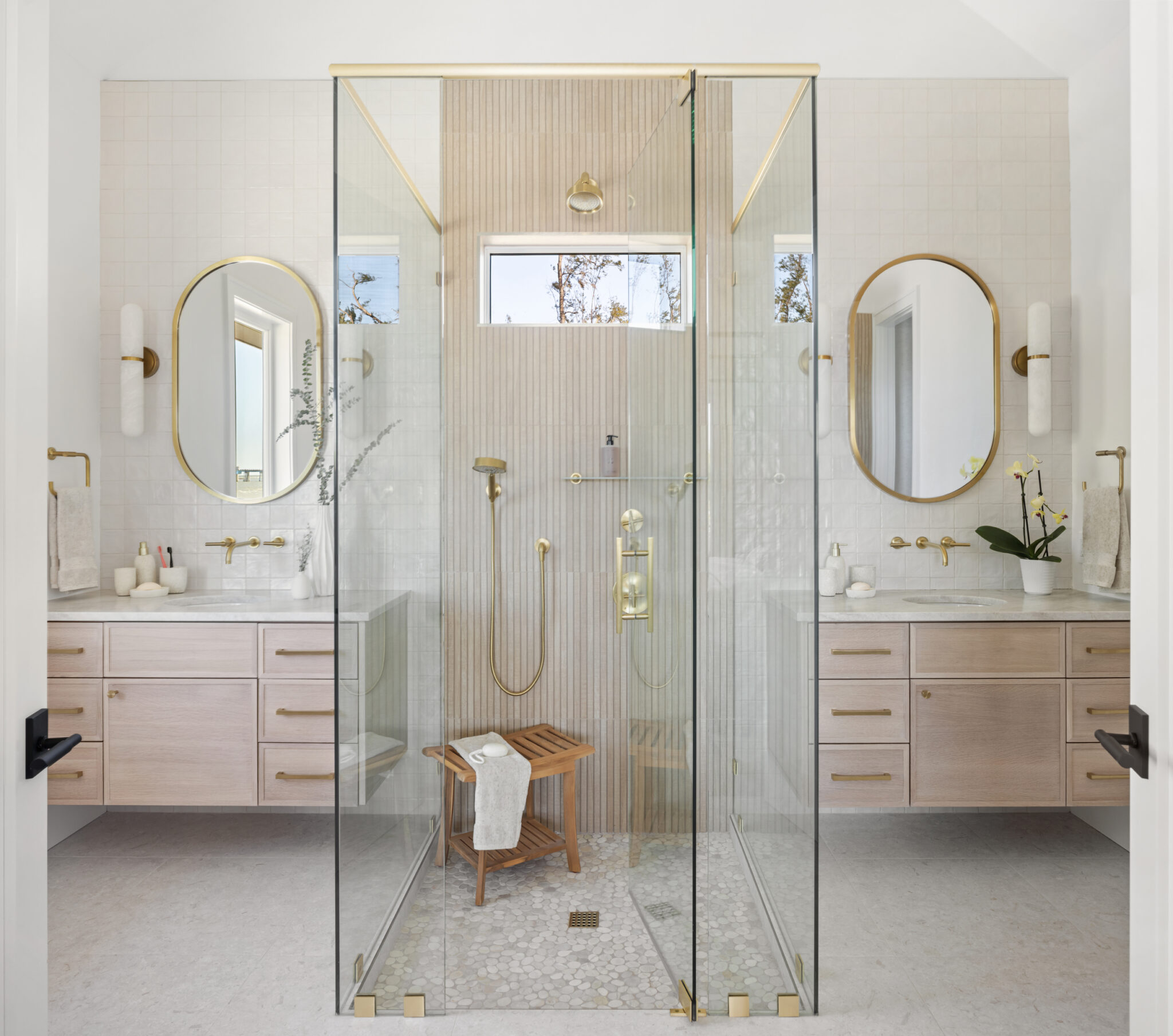 Bath with twin vanities, oval mirrors and a glass shower