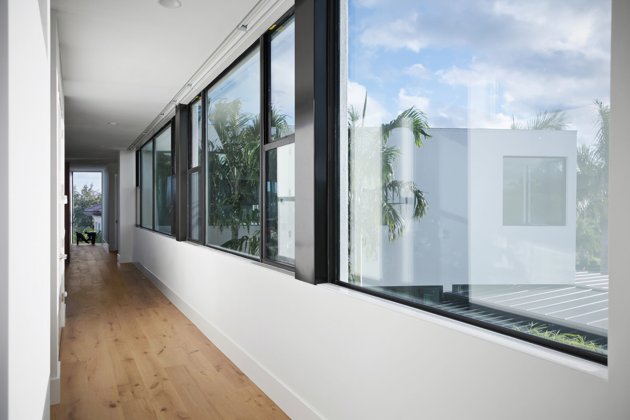 Glass-walled hallway looking out to a white cantilevered volume