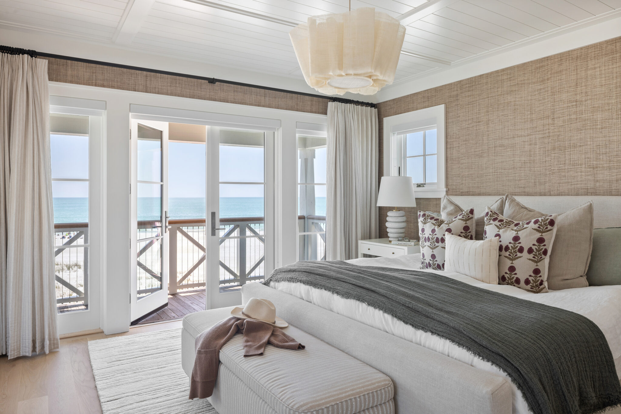 Primary bedroom with grasscloth walls and French doors to a Gulf-view balcony