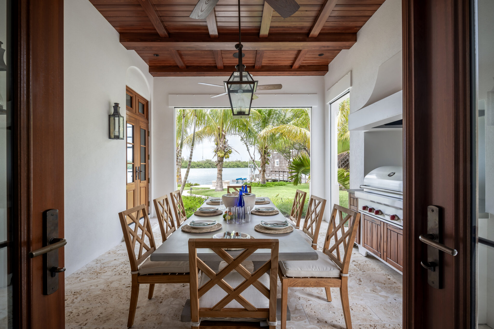 Covered loggia dining table with an outdoor kitchen and garden view