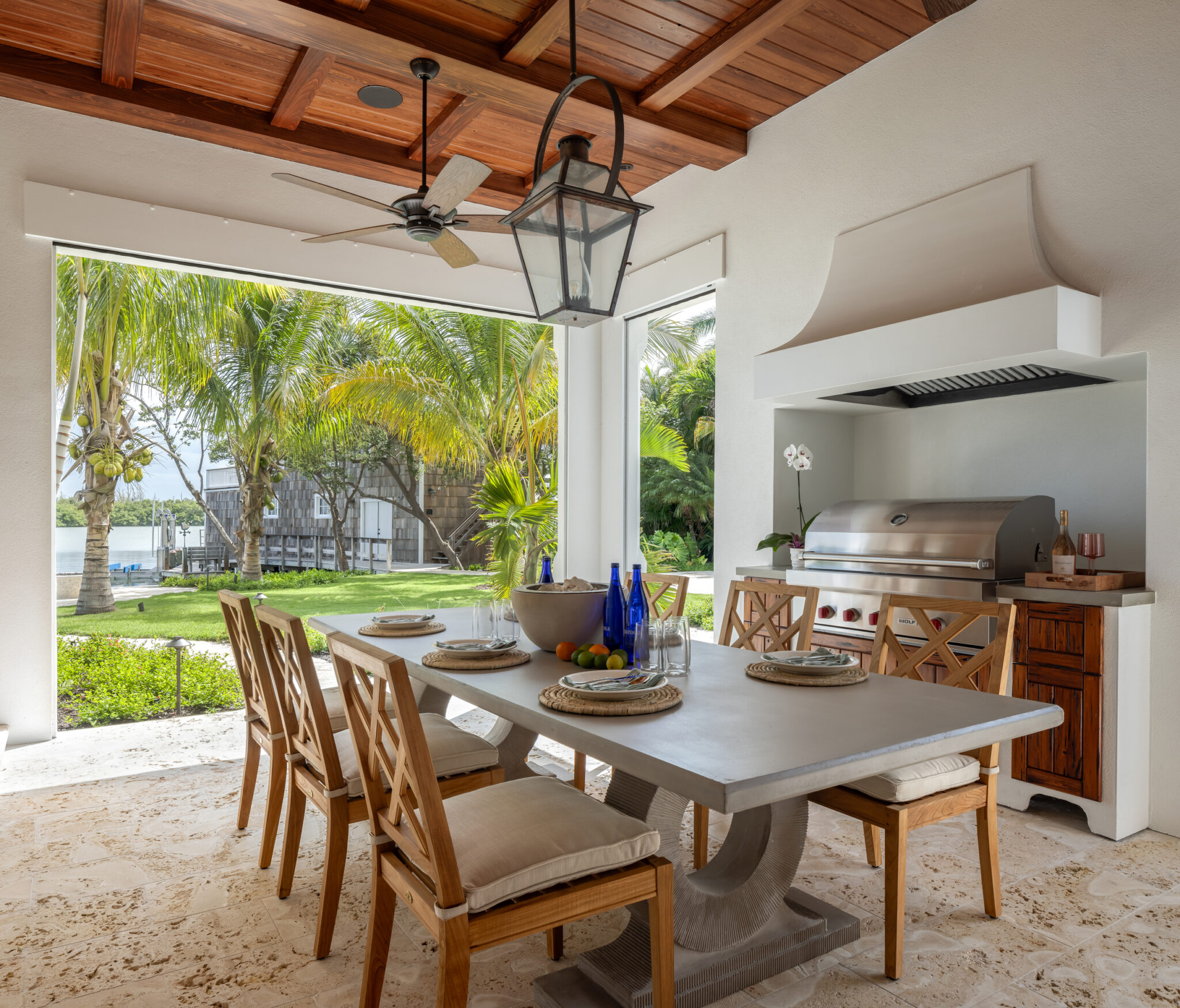 Outdoor kitchen and dining table under a beamed loggia ceiling