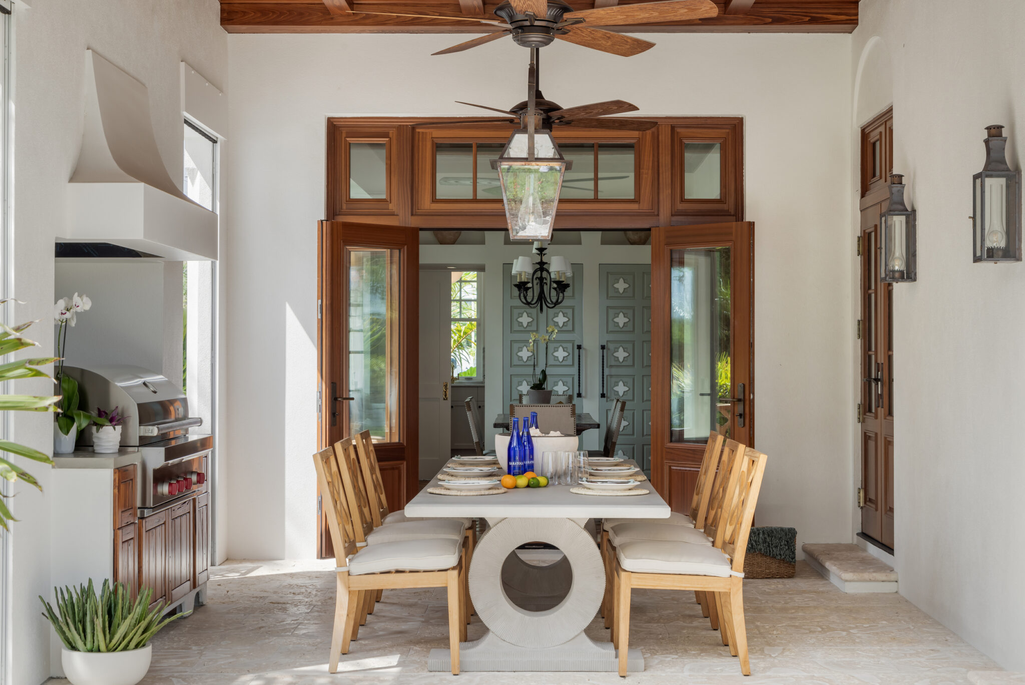 Loggia dining table framed by wood French doors and lanterns
