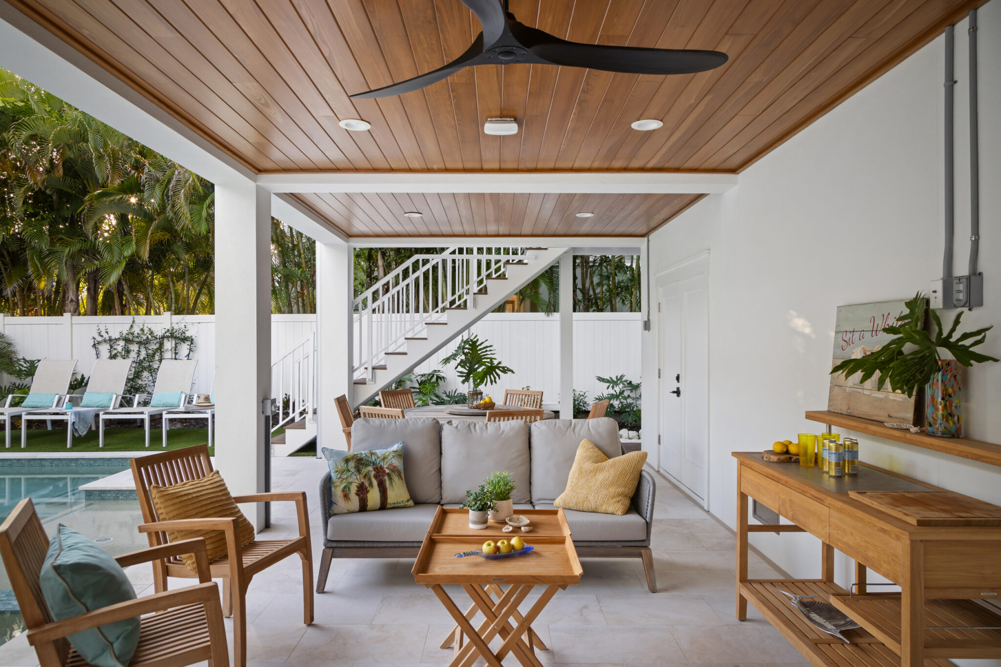 Covered lanai under the house with a wood ceiling, beside the pool