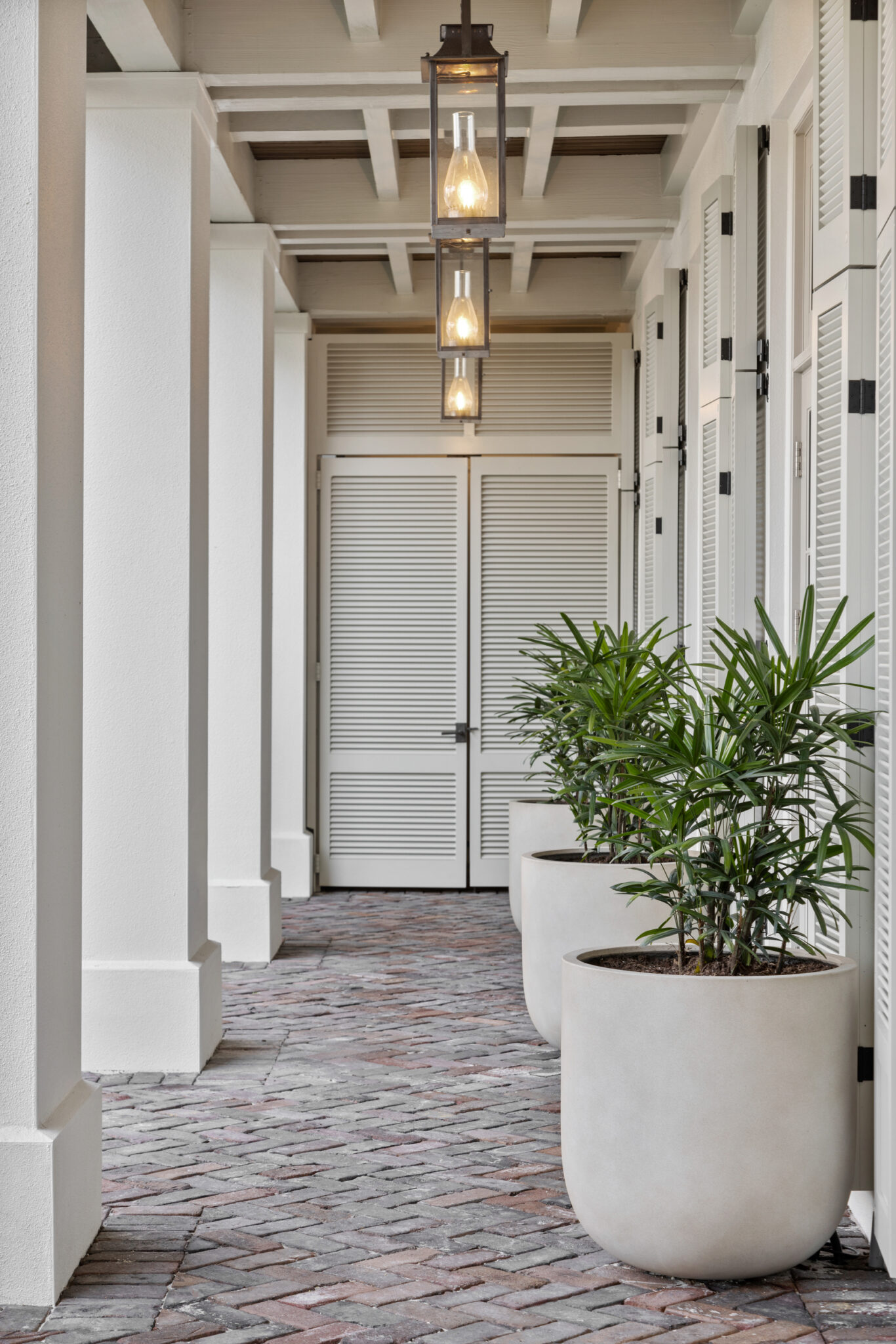 Covered loggia with brick pavers and potted palms