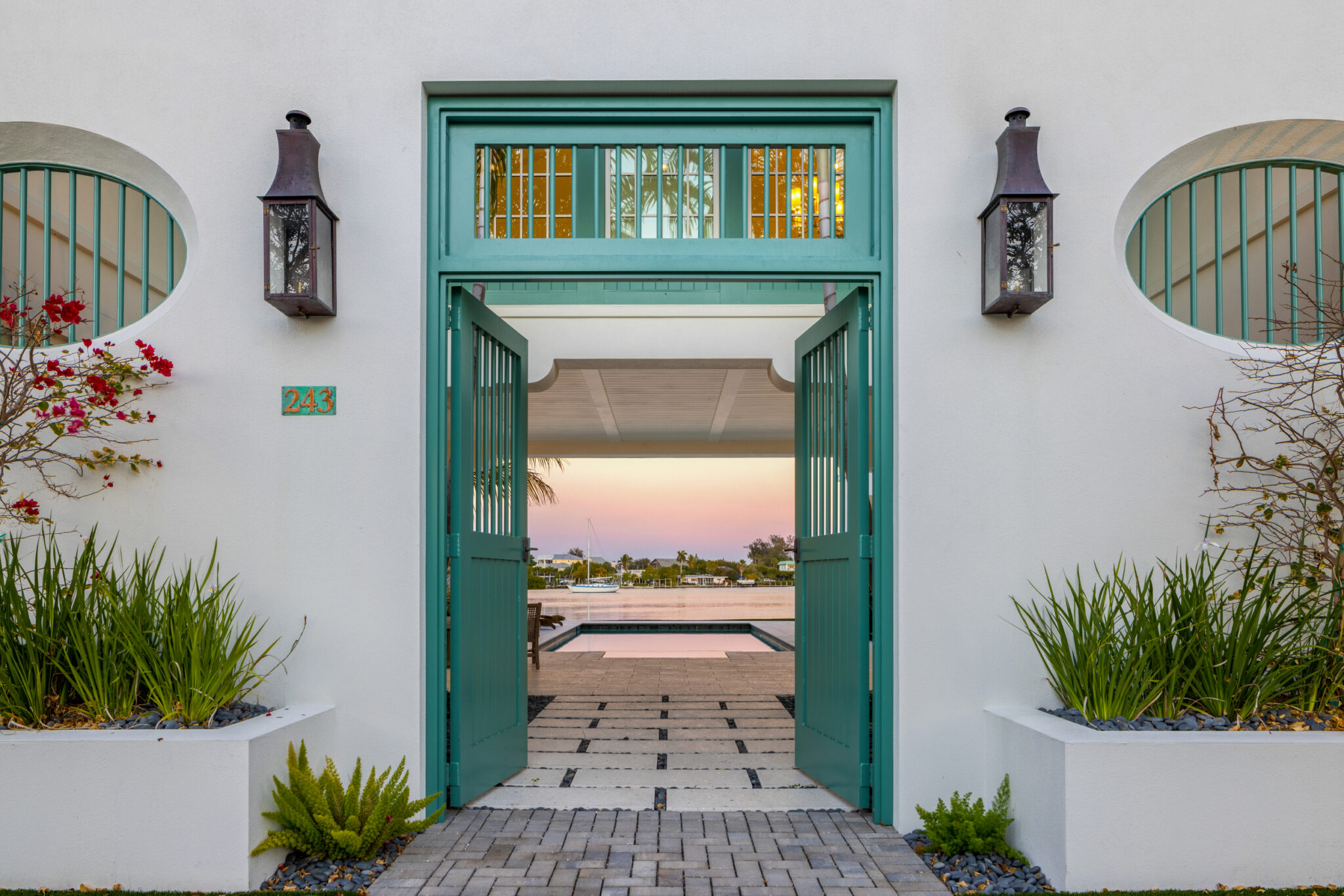 Green double doors in a white stucco wall opening to the courtyard and bay