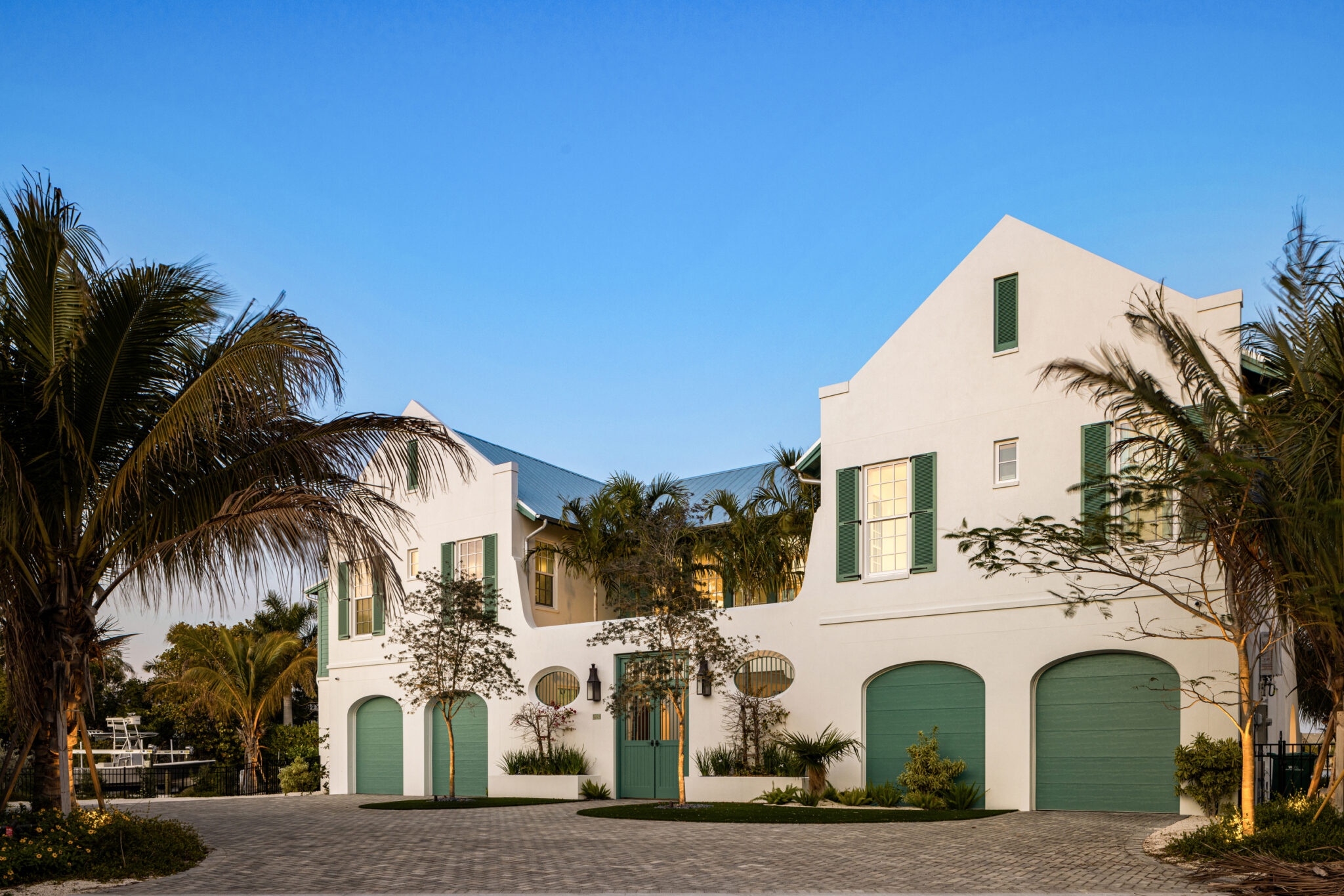 Bimini Bay House with white stucco, stepped gables and green garage doors
