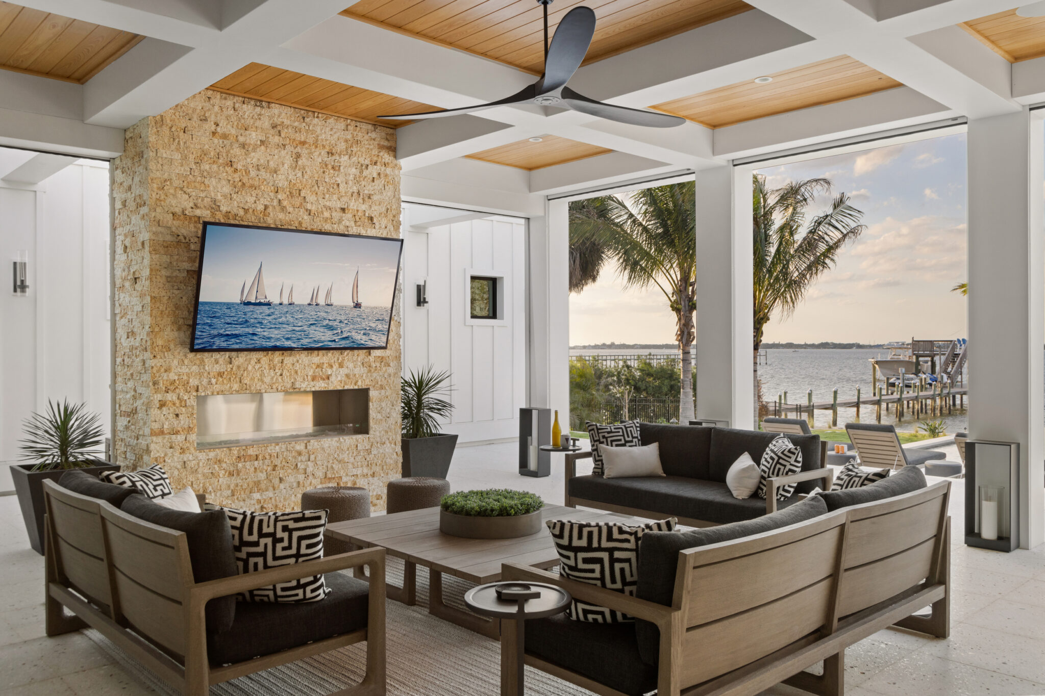 Covered outdoor living room with a stone fireplace wall and river views