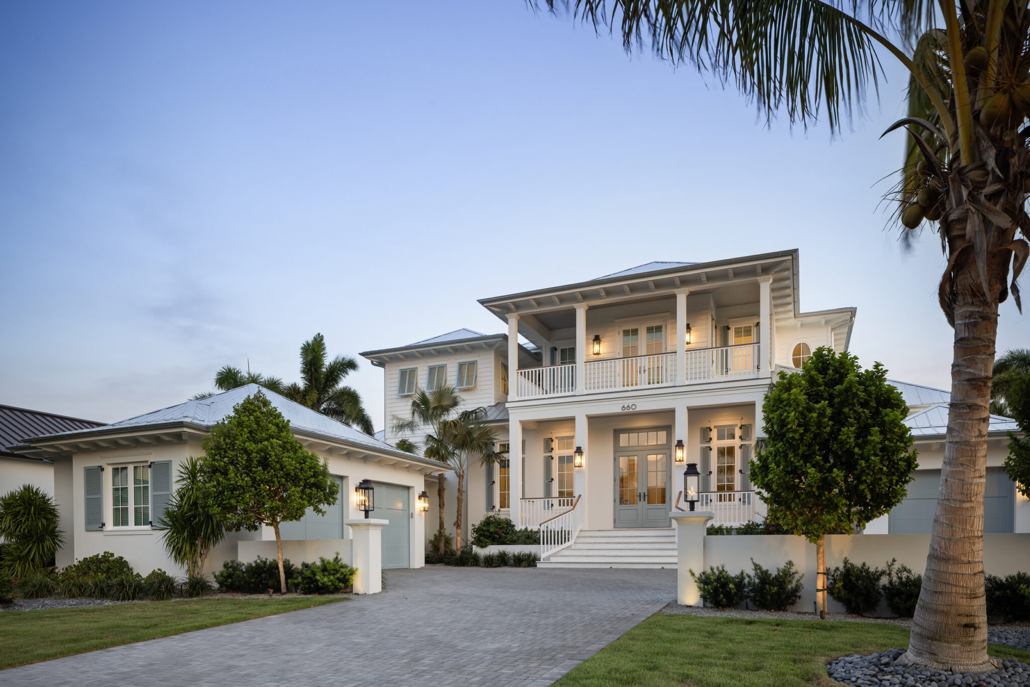 Harbor House with two-story porches and palms, from the paver drive