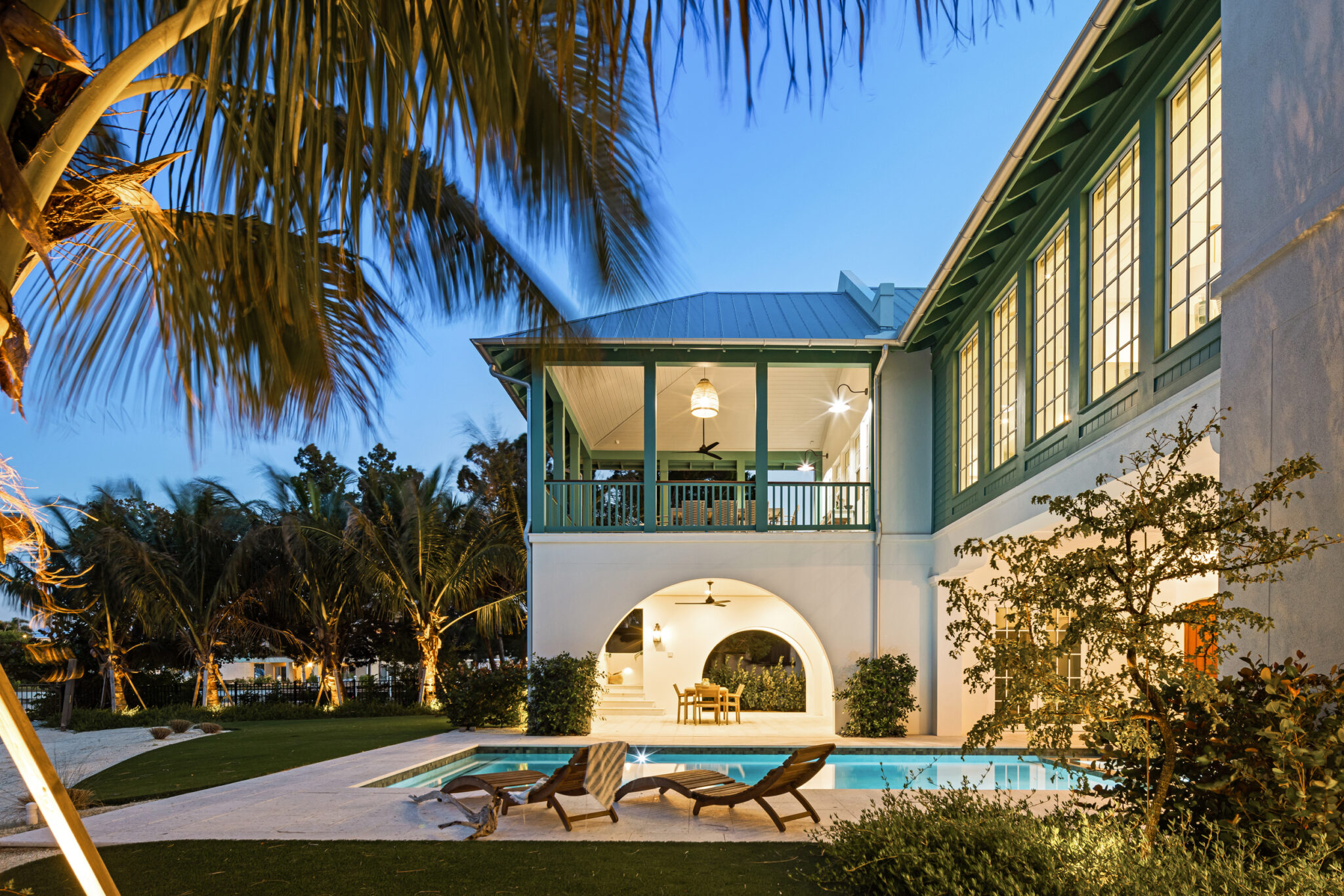 Upper porch with green trim above the pool and palms