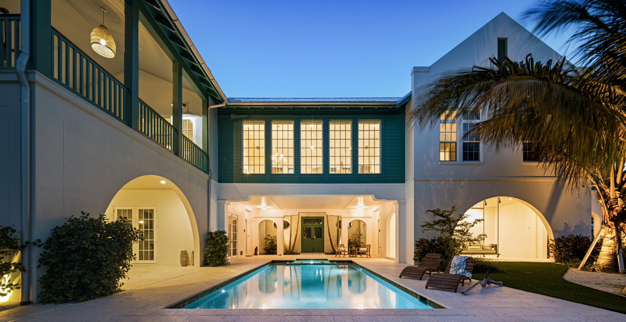 Courtyard pool lit at dusk between the arched wings of the house