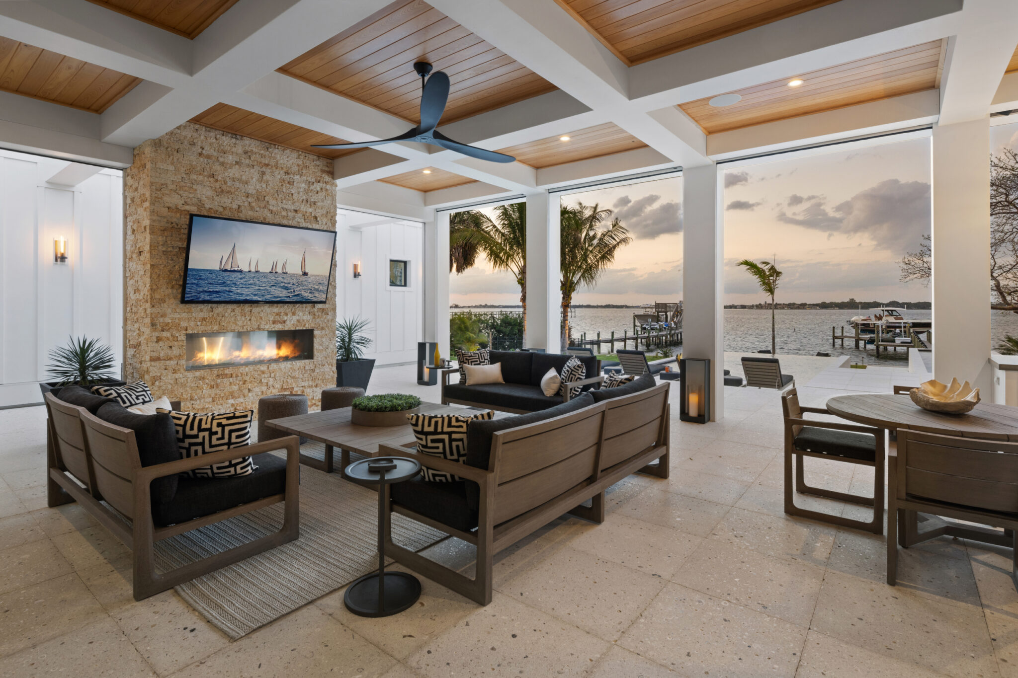 Outdoor living room with a fireplace and coffered ceiling, river beyond