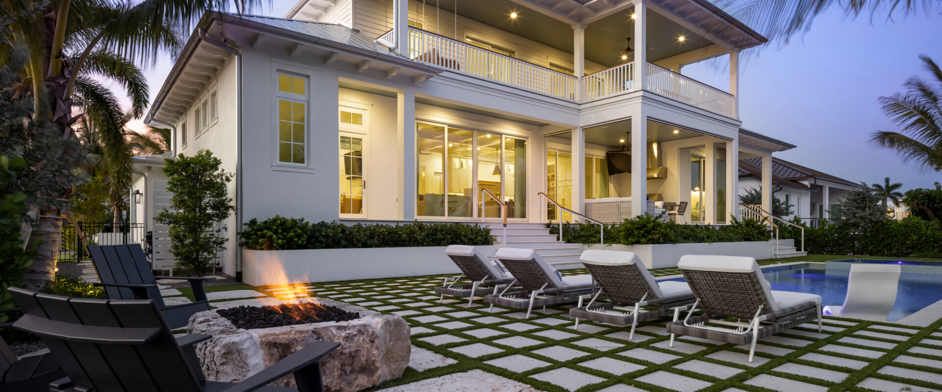 Rear of Harbor House with the pool deck and fire pit at dusk