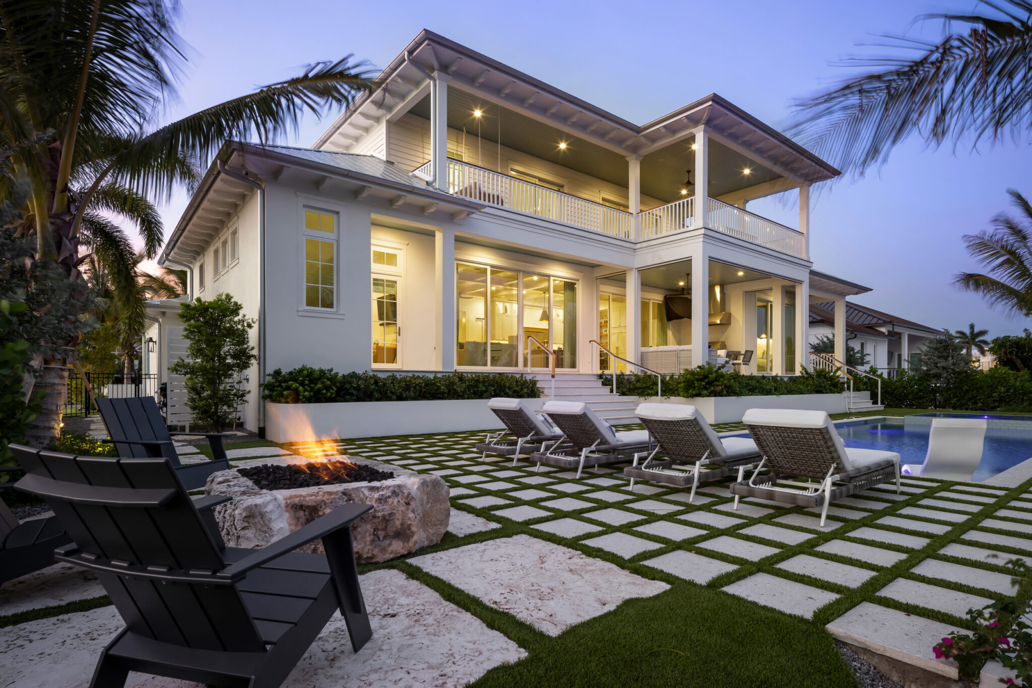 Rear of Harbor House with the pool deck and fire pit at dusk