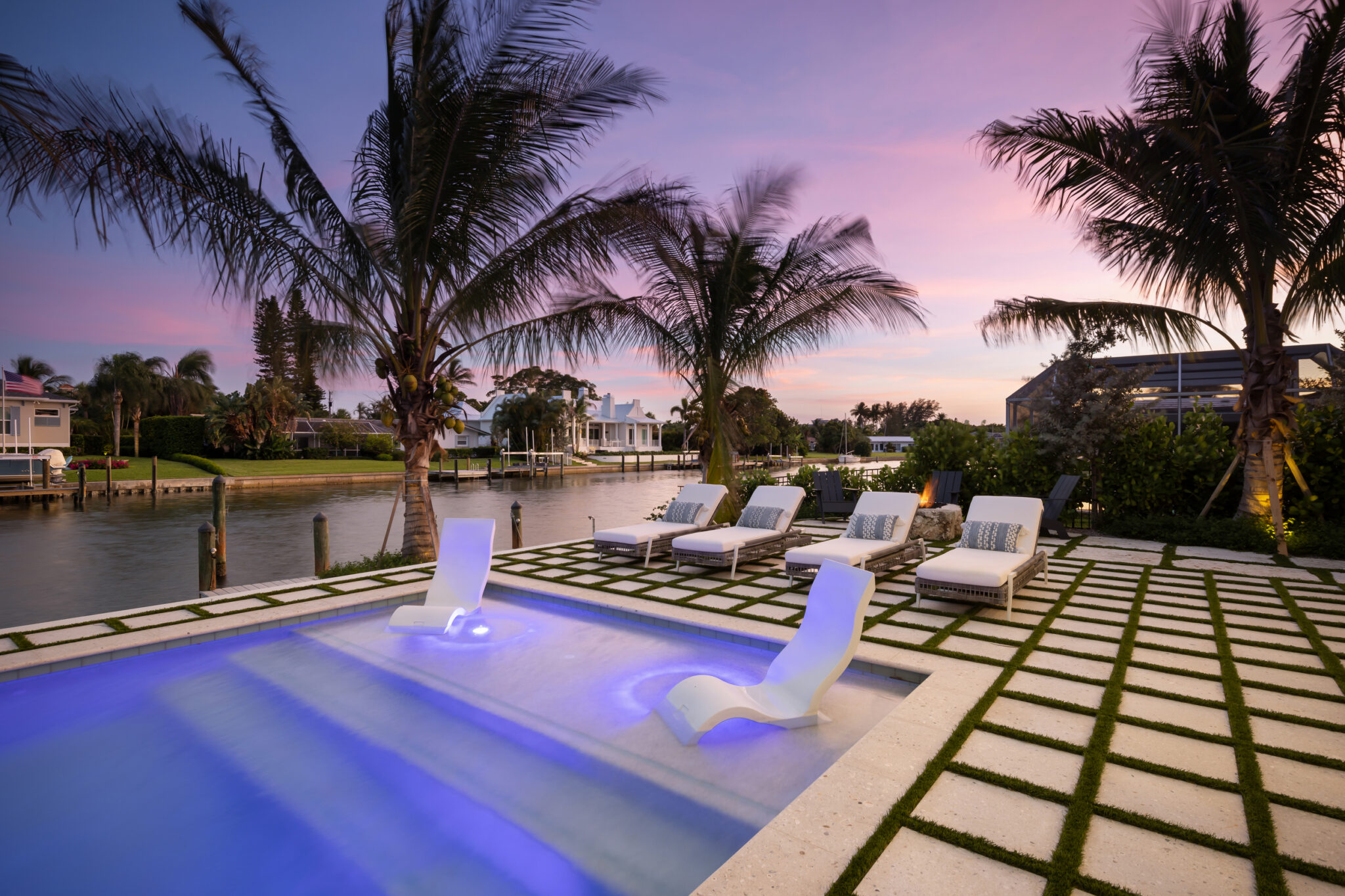 Lit pool and turf-and-paver grid on the canal at dusk