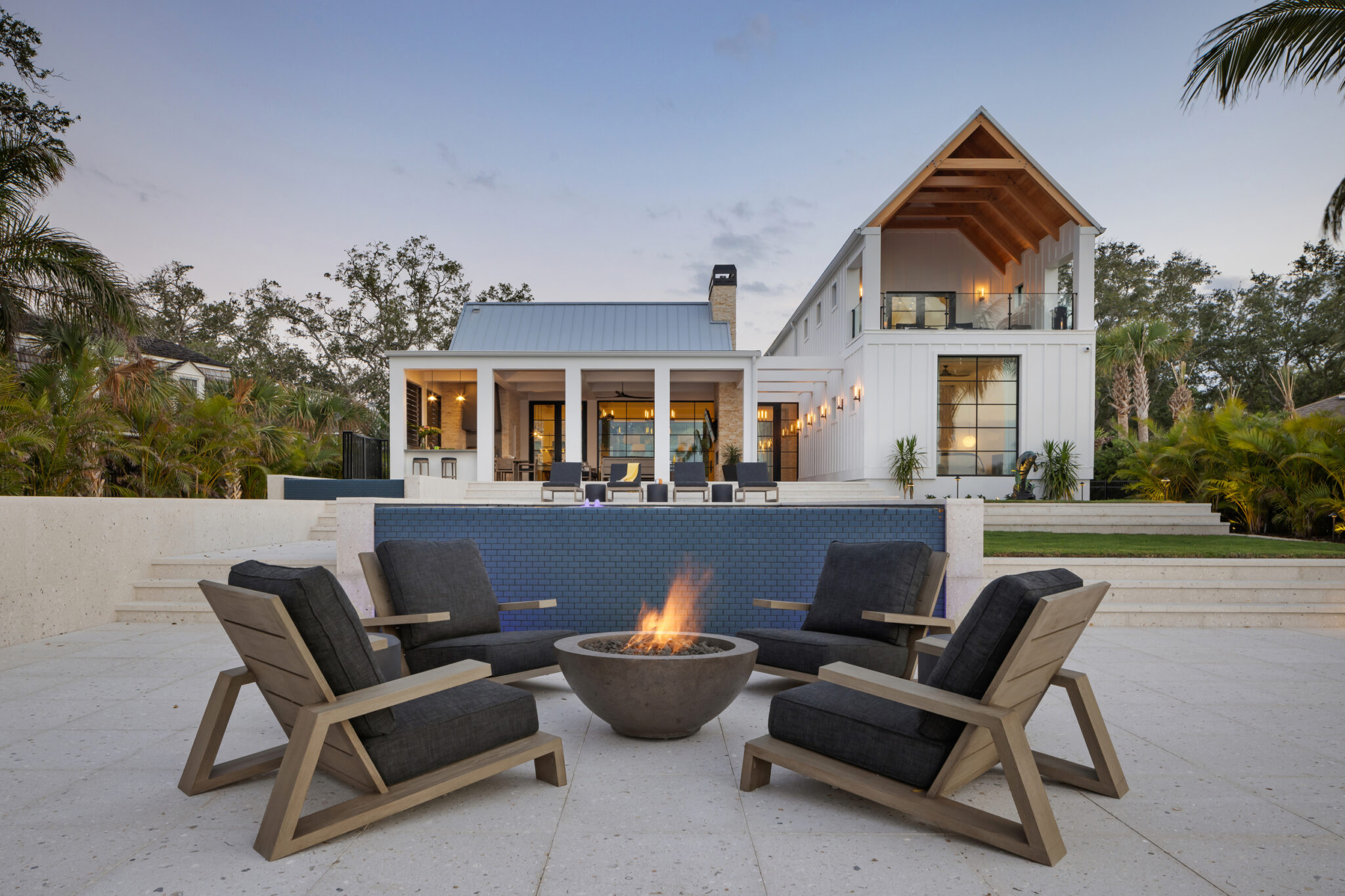 Fire pit and chairs on the terrace below the white gable of the house