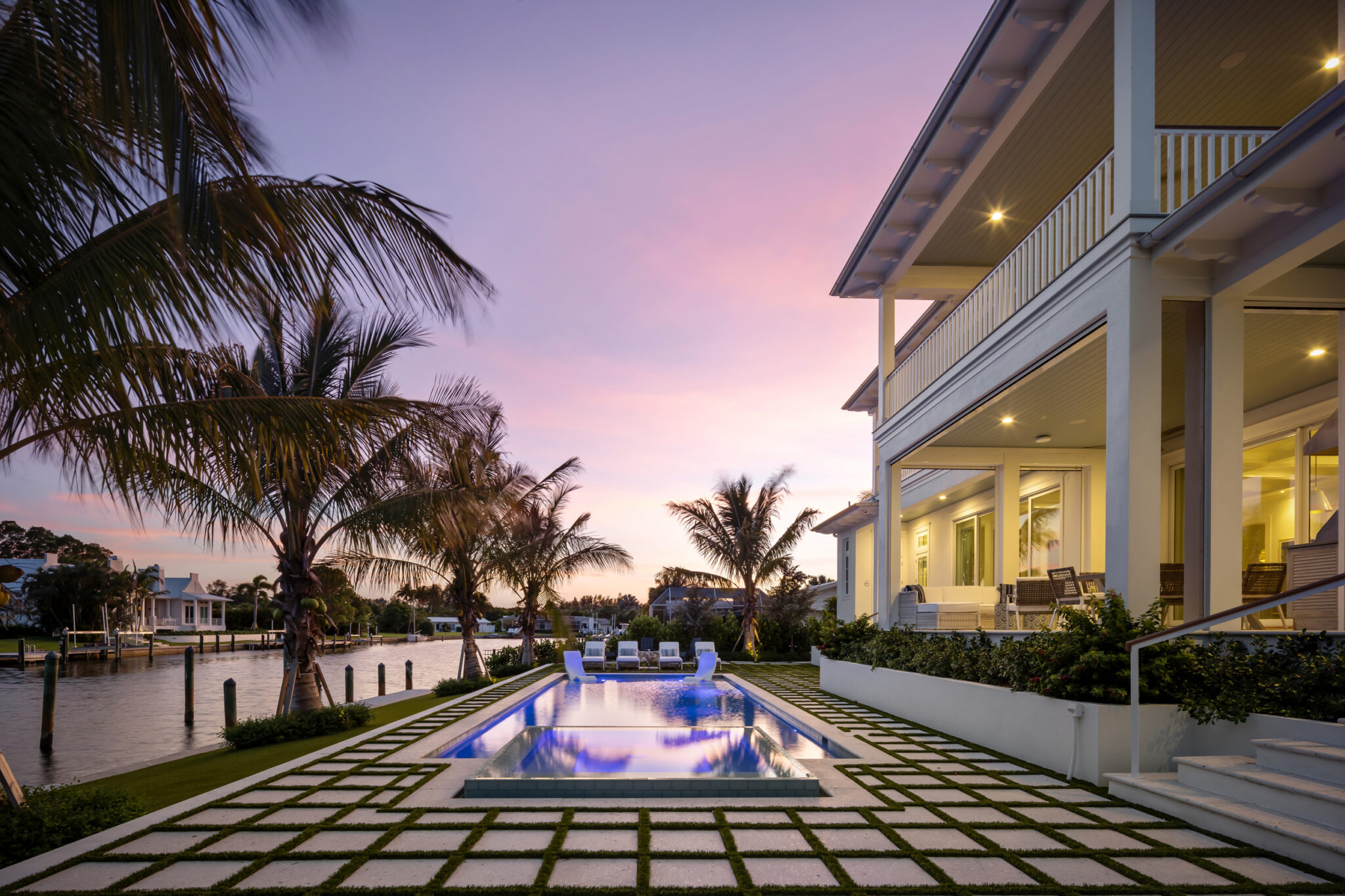 Pool and paver grid beside the two-story rear porches at dusk