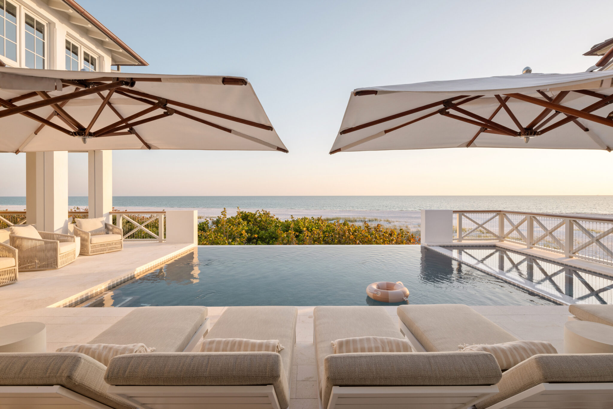 Pool deck with umbrellas and an infinity edge looking out to the Gulf