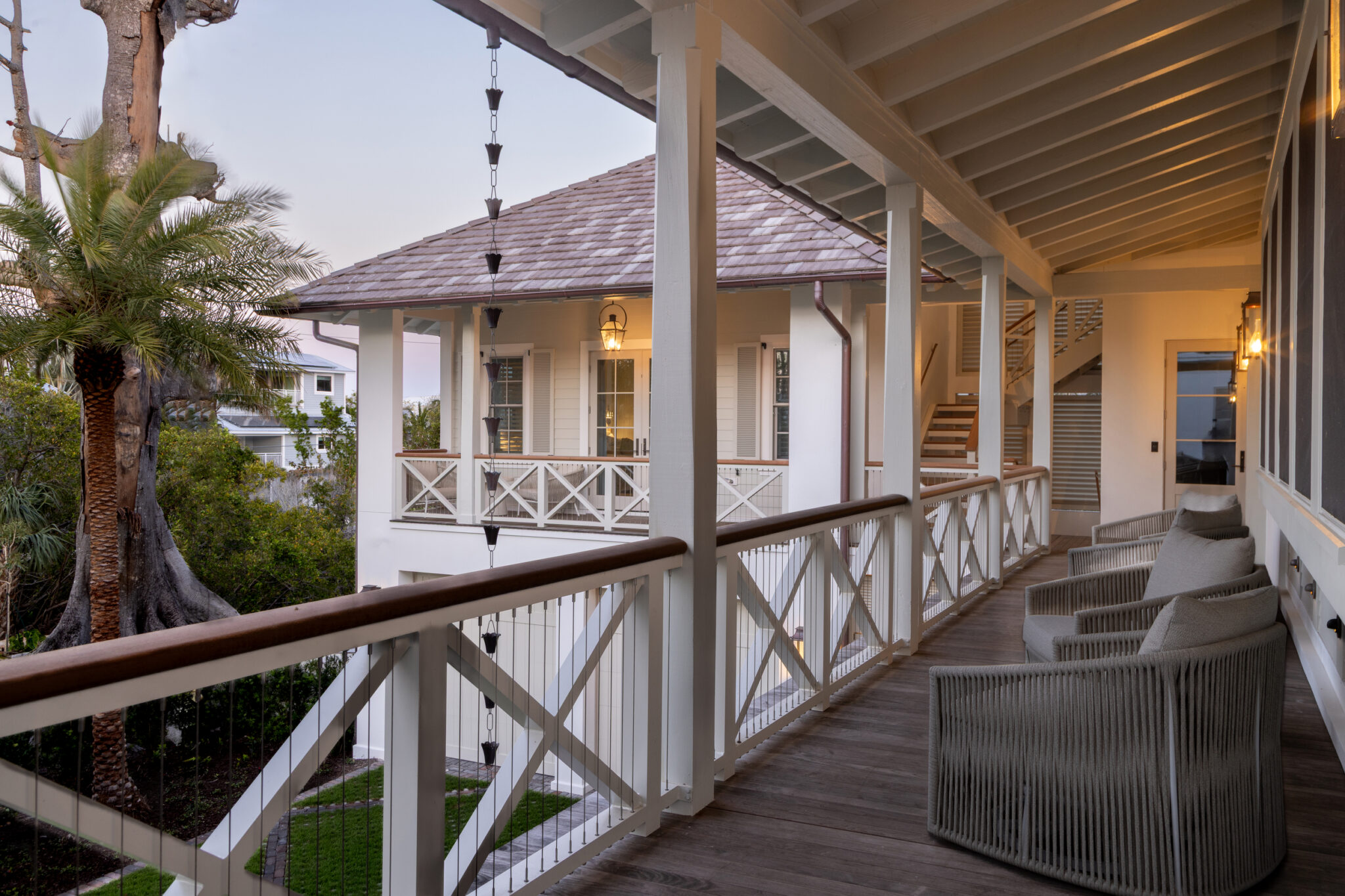 Upper porch with X-pattern railings and wood ceiling at dusk