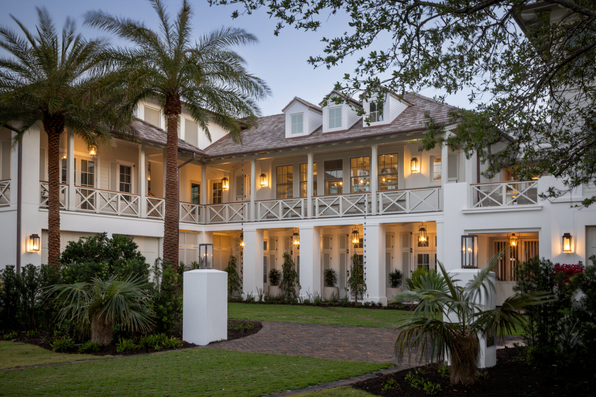 North Shore Residence at dusk, with layered porches, palms and a lit motor court
