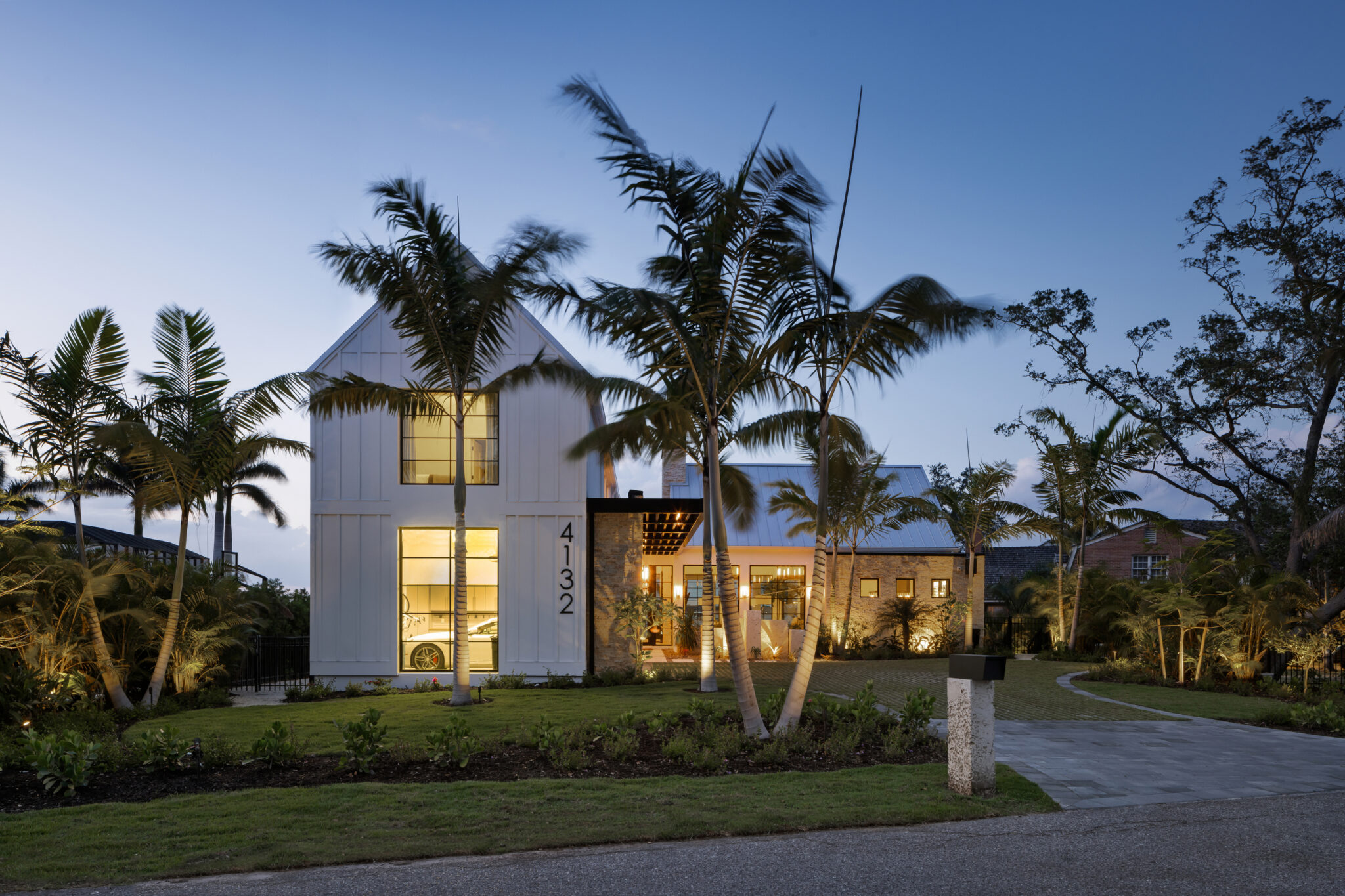 Two-story white gable of Modern River House framed by palms at dusk