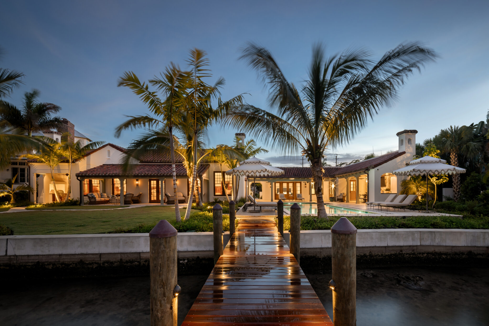 Lit dock leading to the estate and its palms at dusk