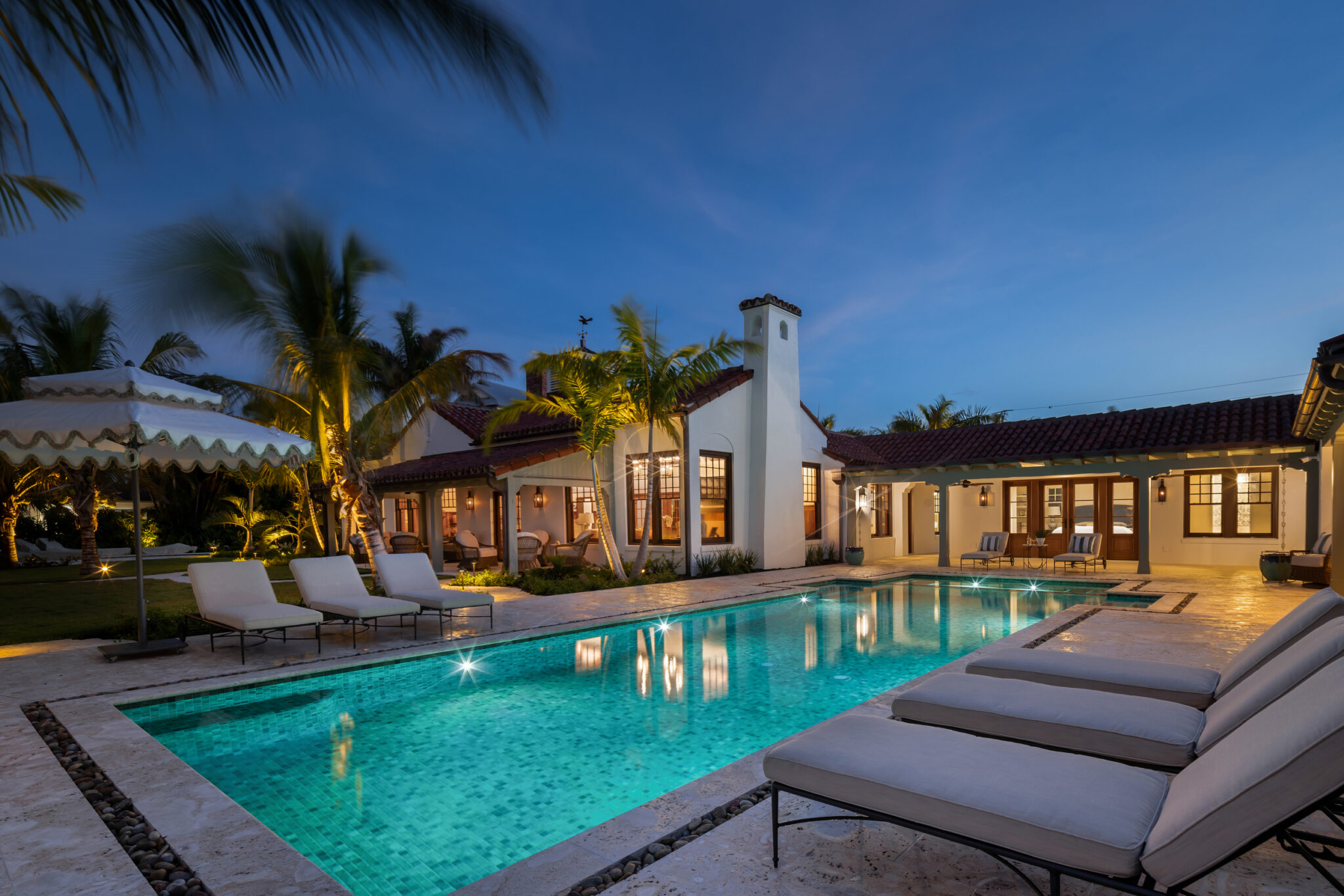 Pool and lounge chairs along the white stucco wings of the estate