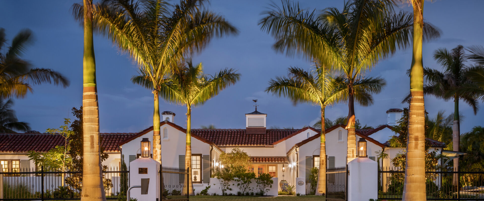 Van Wezel Estate at dusk behind a paver walk lined with royal palms