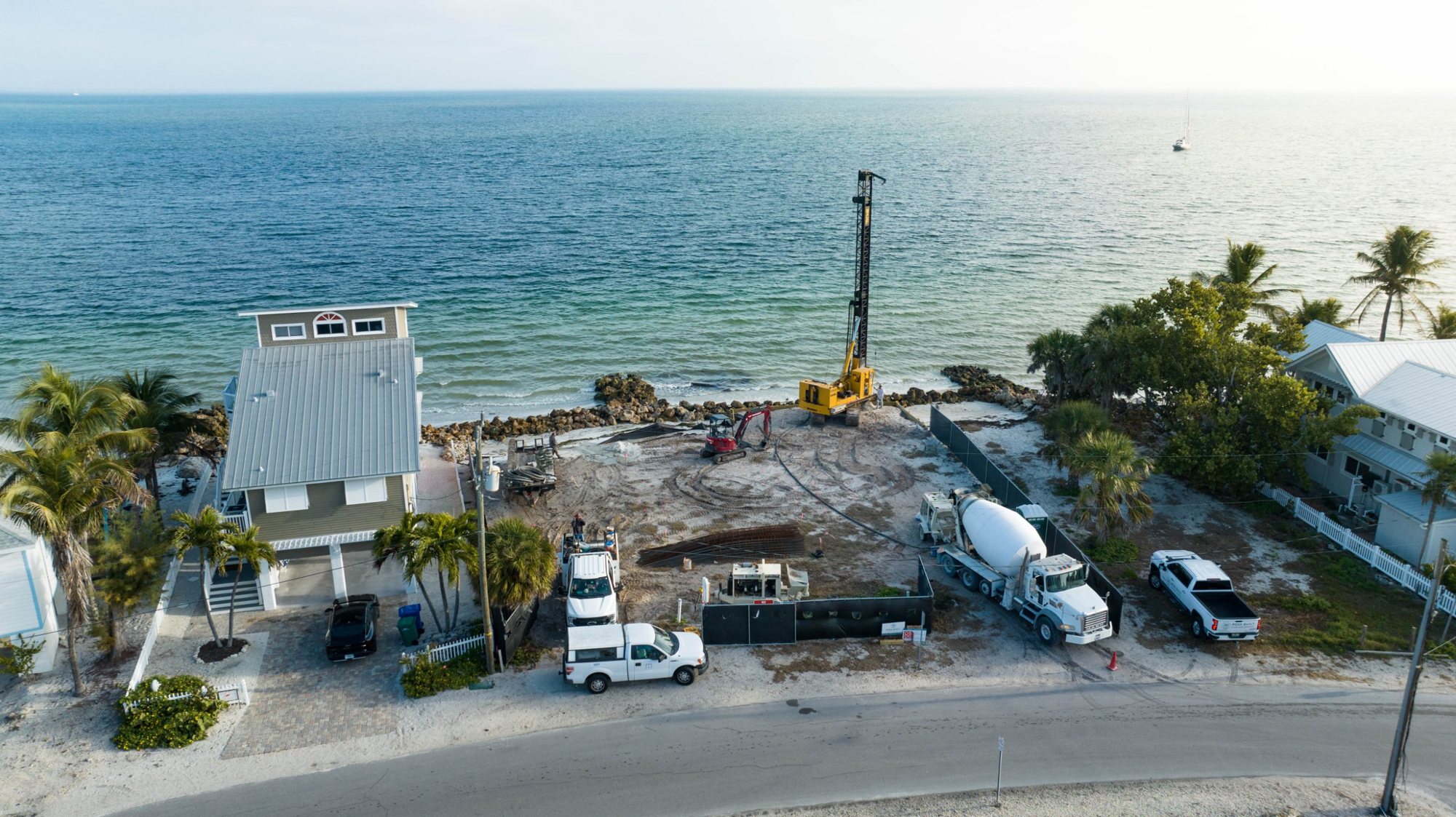 Aerial view from the street of the pile rig at work, with the bay beyond