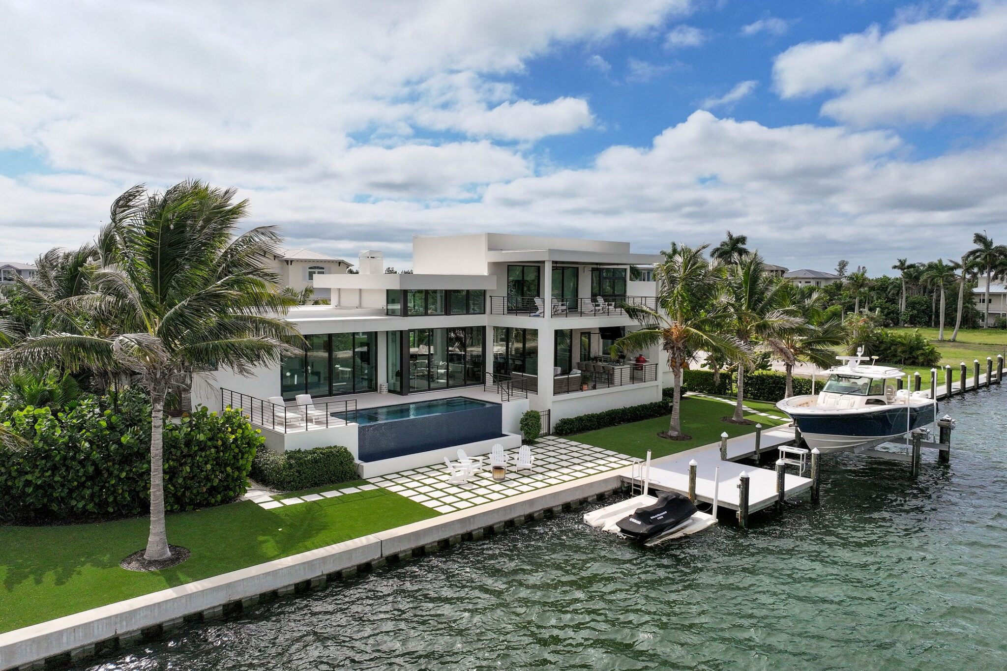 Bay side of Bayview Residence with an infinity-edge pool, lawn pavers, dock and boat lift