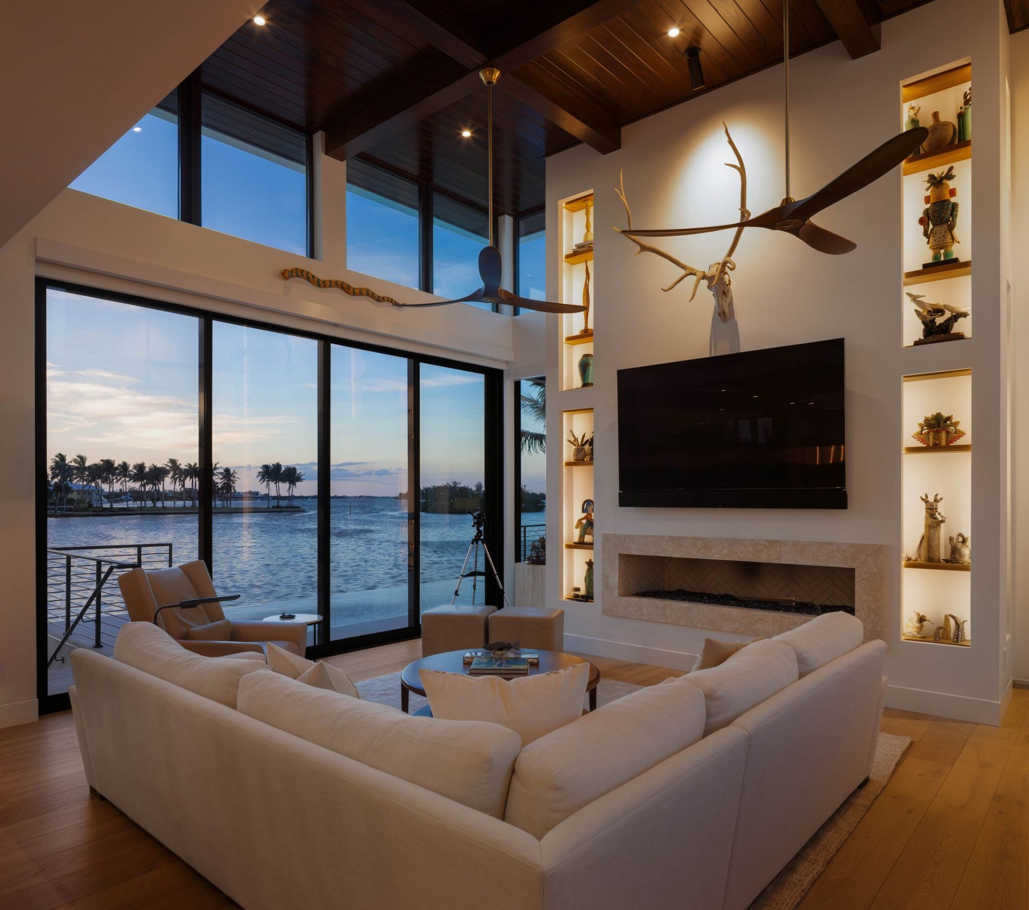 Living room at dusk with lit display niches and sliding glass doors facing the bay