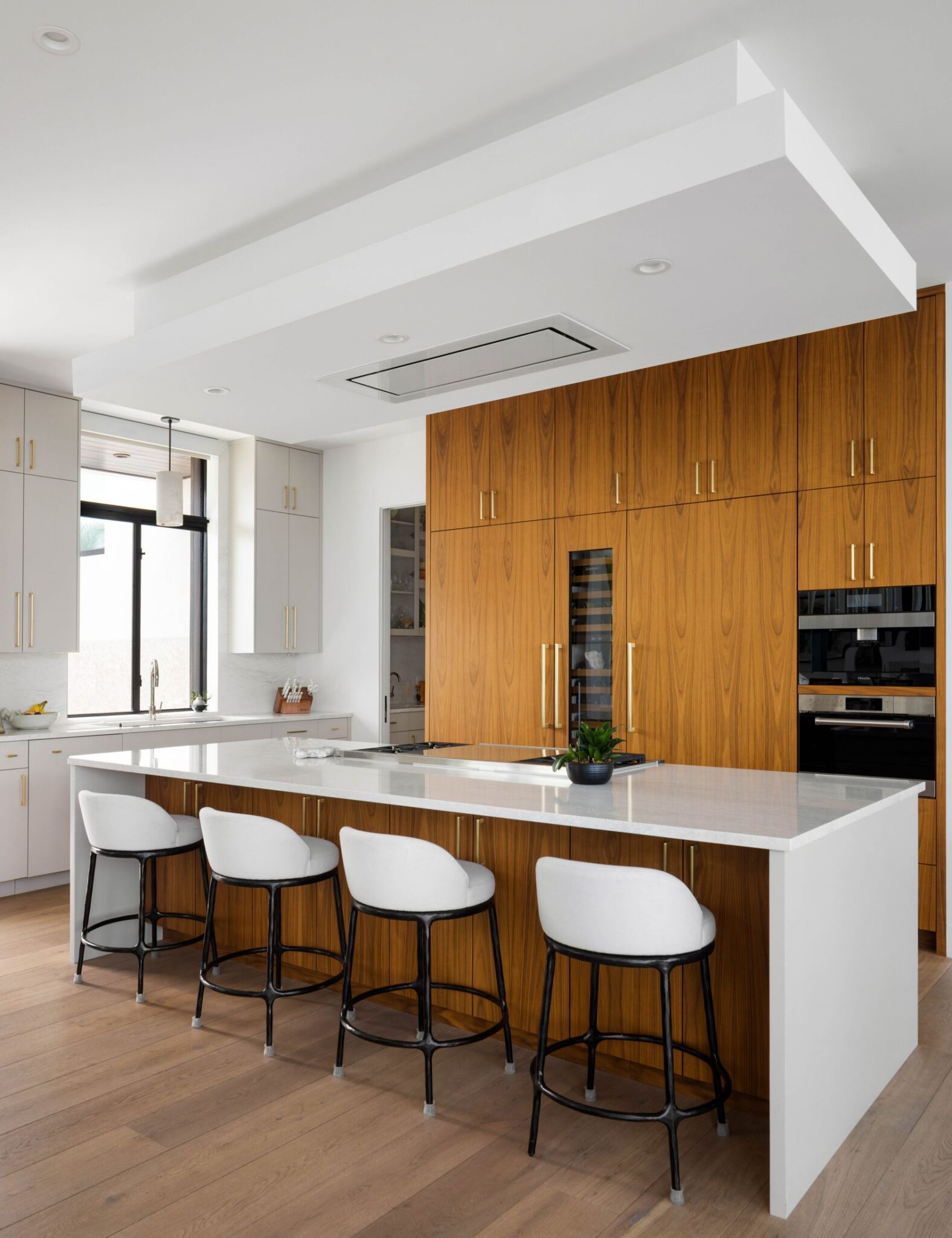 Kitchen island and full-height walnut cabinetry with built-in wine storage