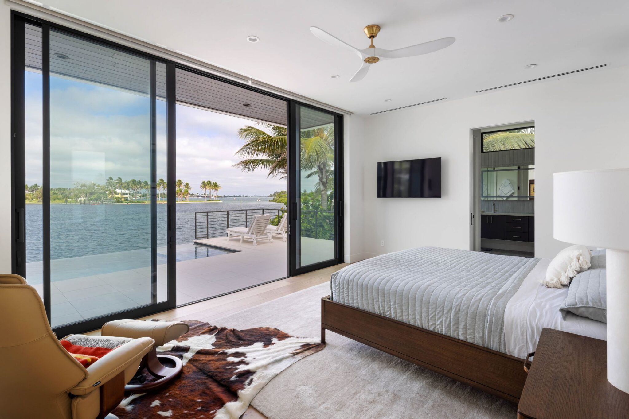 Primary bedroom with a wall of sliding glass opening to the pool deck and bay