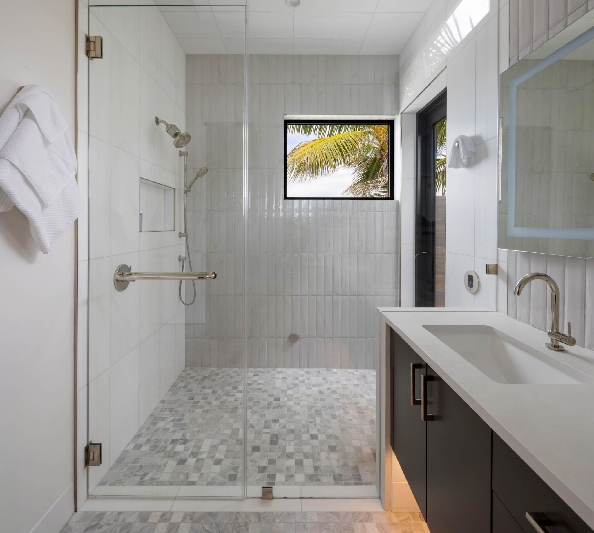 Walk-in shower with vertical tile and a high window to the palms