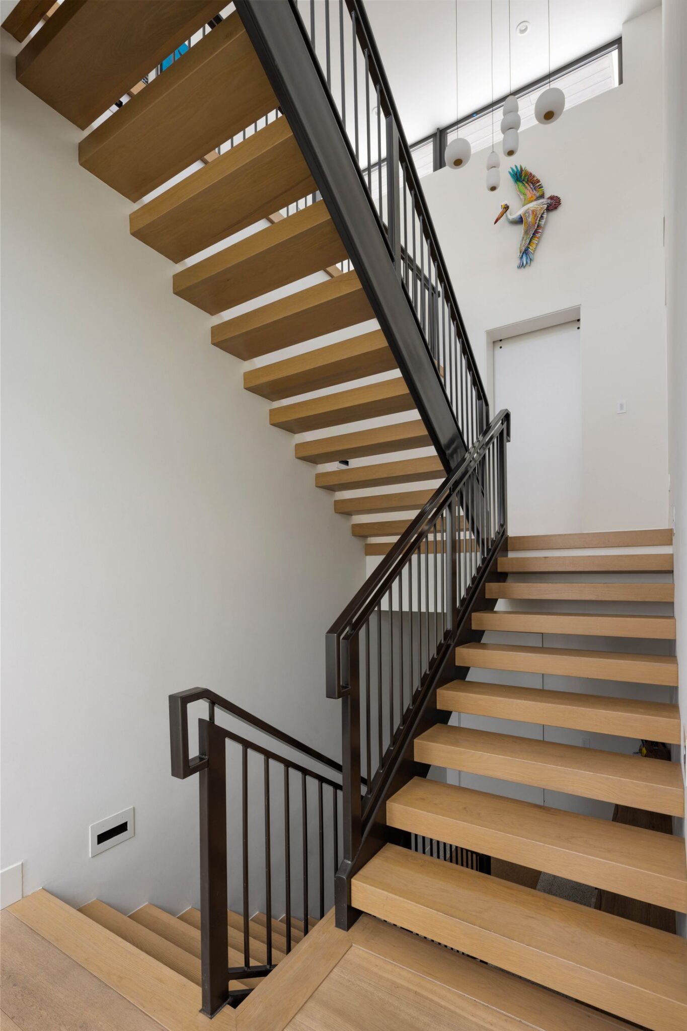 Open-tread floating stair with oak treads and a black steel railing