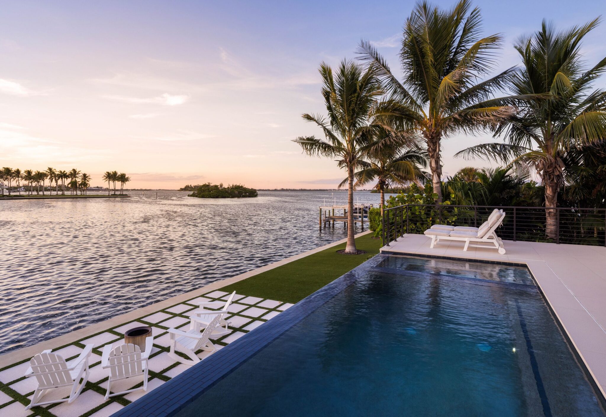 Infinity-edge pool and lawn pavers facing the bay at sunset