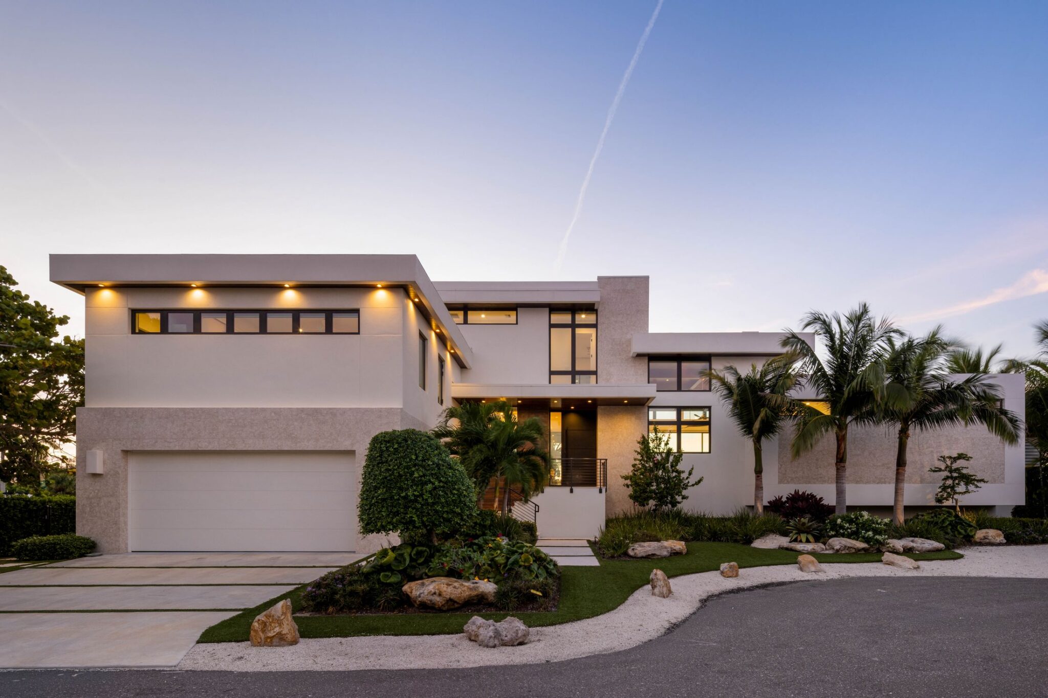 Front elevation at twilight with the garage wing and landscape lighting lit