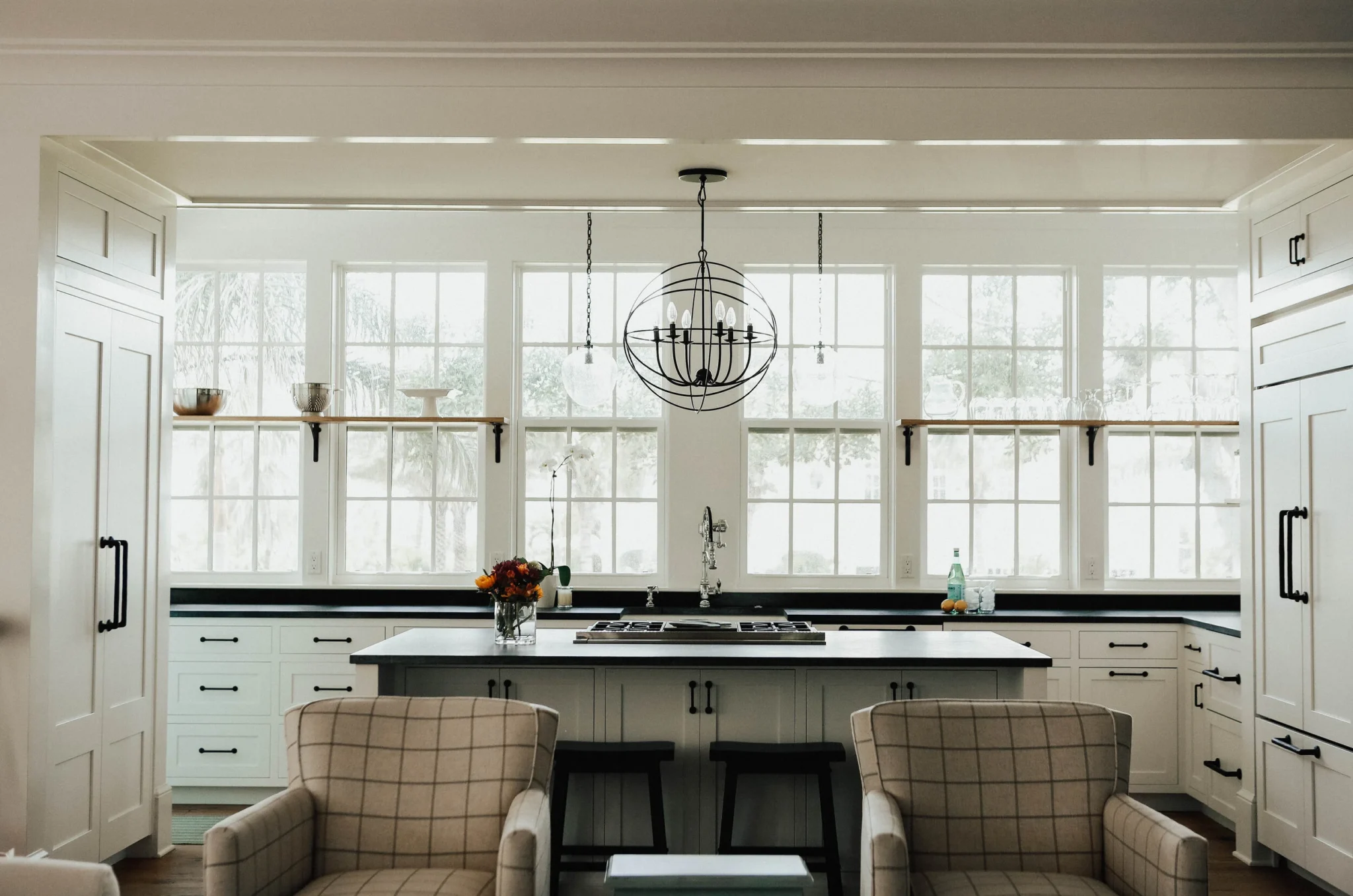 A modern kitchen with white cabinetry, a central island, and large front-facing windows