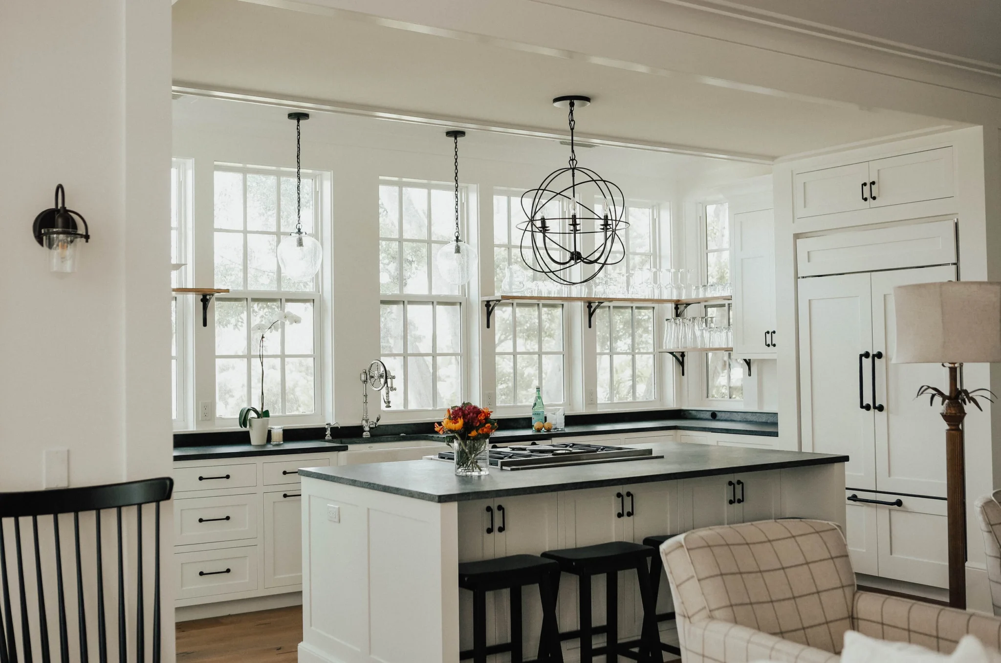 Modern kitchen with white cabinets, black hardware, black countertops, and large windows