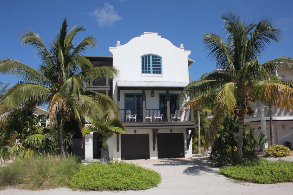 White stucco home in Anna Maria with a curved parapet and palms, completed by Ross Built in 2017