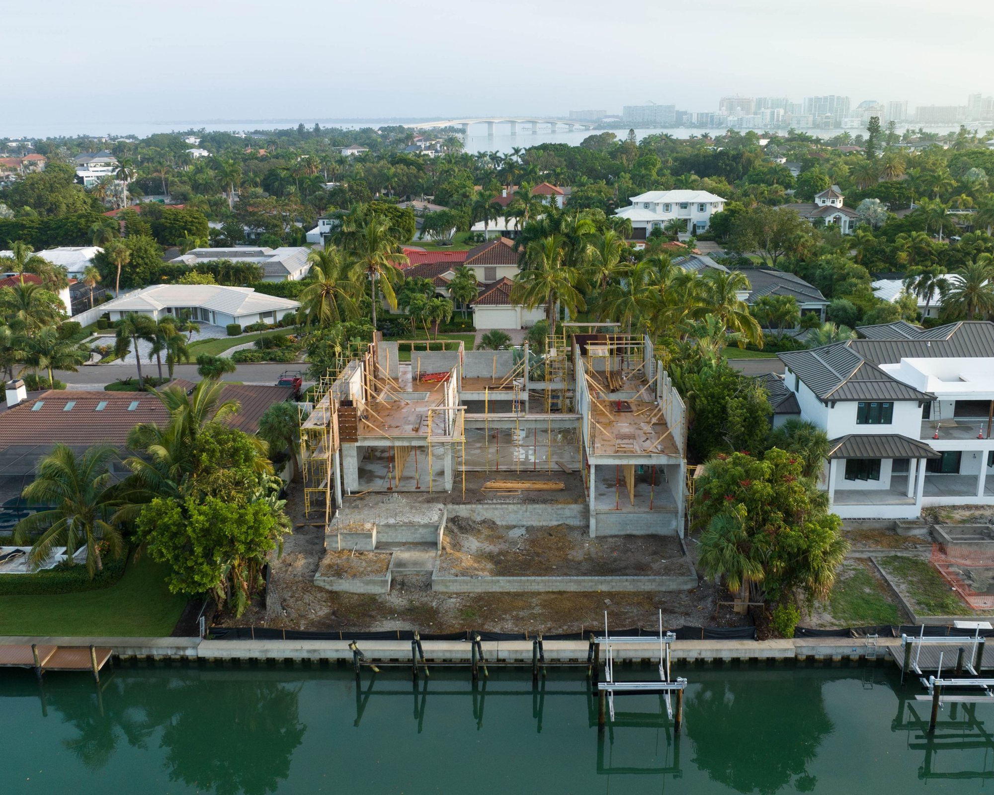 Aerial view from the canal of the first floor walls going up, with the Ringling Bridge beyond
