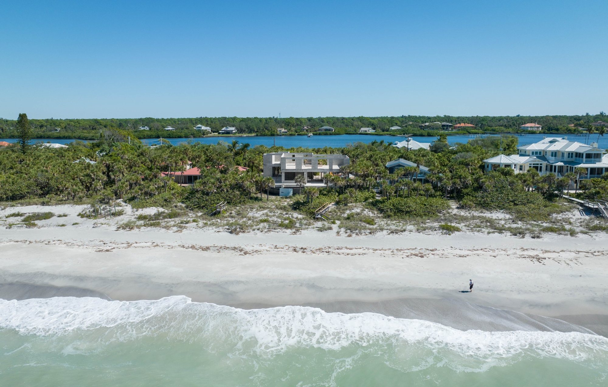 Wide aerial view from the Gulf of the house under construction behind the dunes