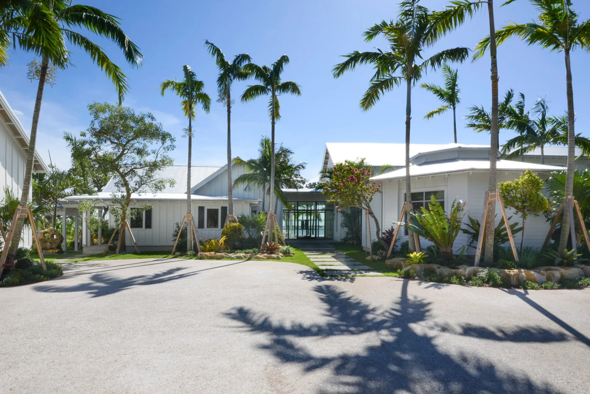White houses with metal roofs surrounded by palm trees and landscaped garden on sunny day