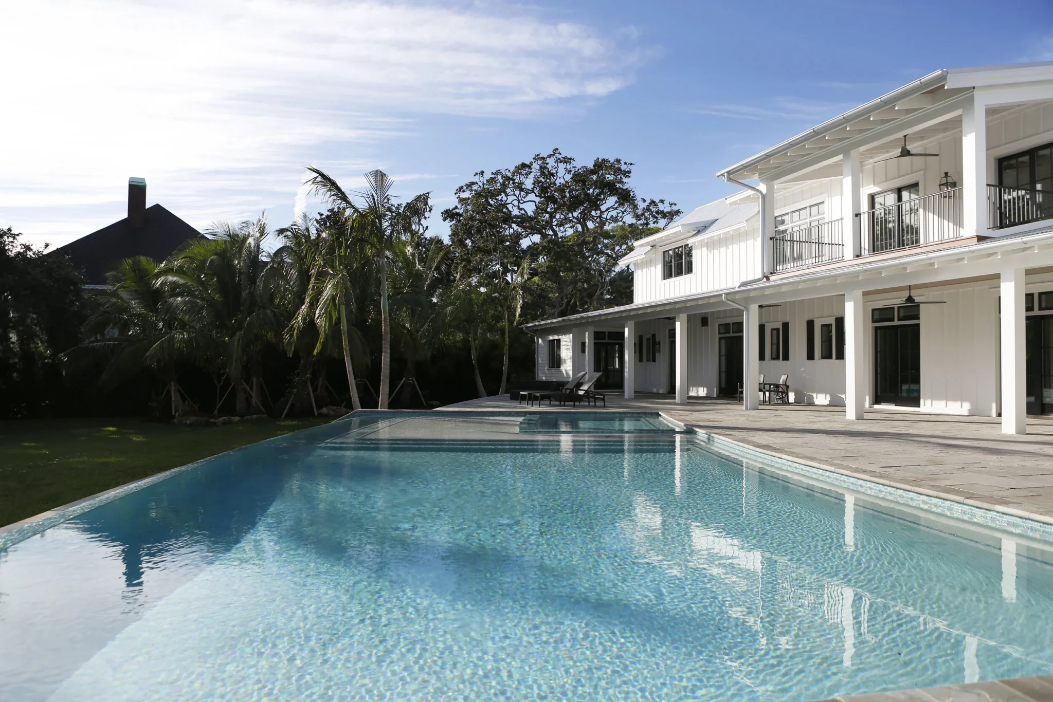 Modern white house with a two-story balcony, outdoor patio furniture