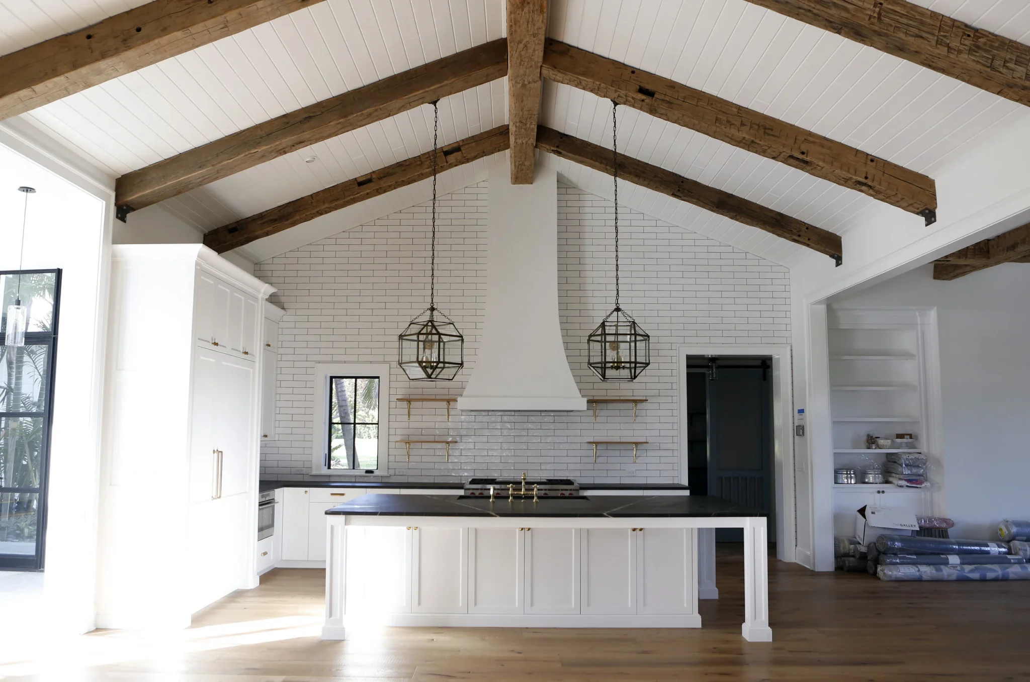 Modern kitchen with white cabinets, black countertop, and white brick wall