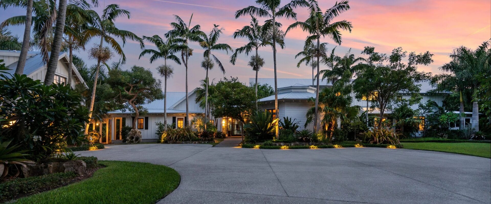 Entry court of a white modern farmhouse at dusk, framed by palms