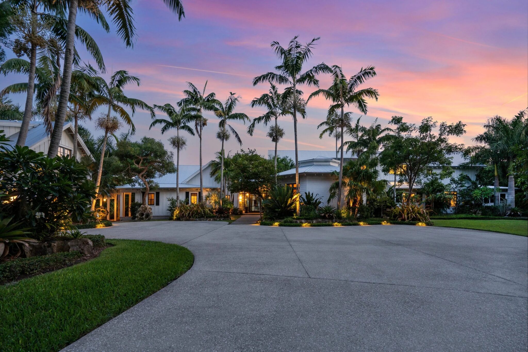 Entry court of a white modern farmhouse at dusk, framed by palms