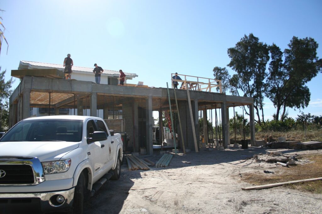 Greg Ross with the framing crew on top of Ross Built’s first new beachfront home on Anna Maria Island, his truck parked in front, 2010
