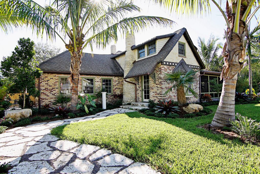 Historic brick home in Anna Maria after its restoration by Ross Built, with a stone path and palms, 2016