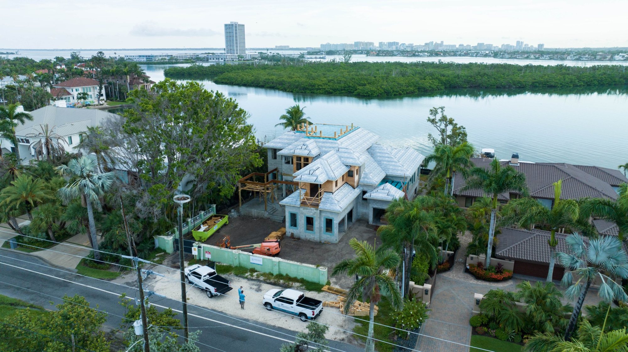 Aerial view from the street of the house under construction, with the bay and downtown Sarasota beyond